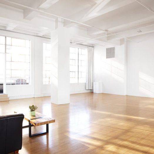 large bar room with cascading light coming in through large windows & a couch to sit at