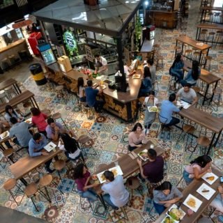 Happy group of Latin American people eating at a food court - food and drinks concepts